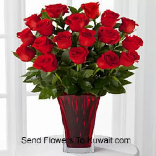 18 roses rouges avec des garnitures saisonnières dans un vase en verre décoré d'un nœud rose